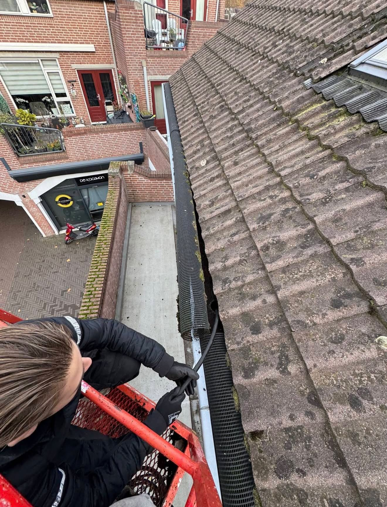 KWS aan het werk bij het reinigen van een dakgoot vanuit een hoogwerker